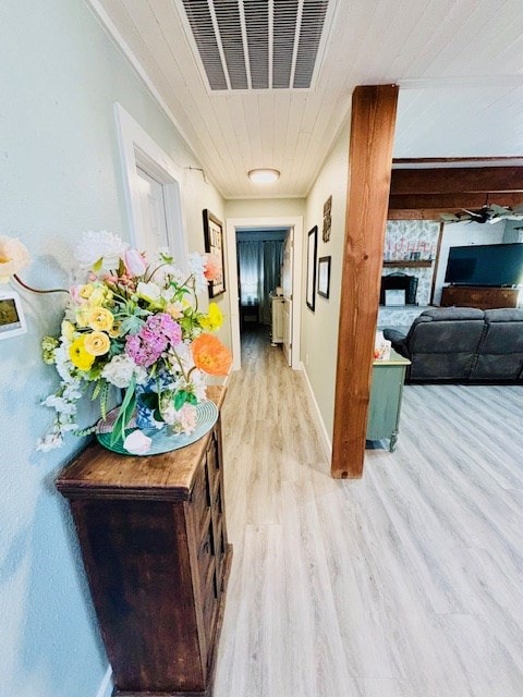 hallway featuring light wood-style floors, baseboards, and visible vents