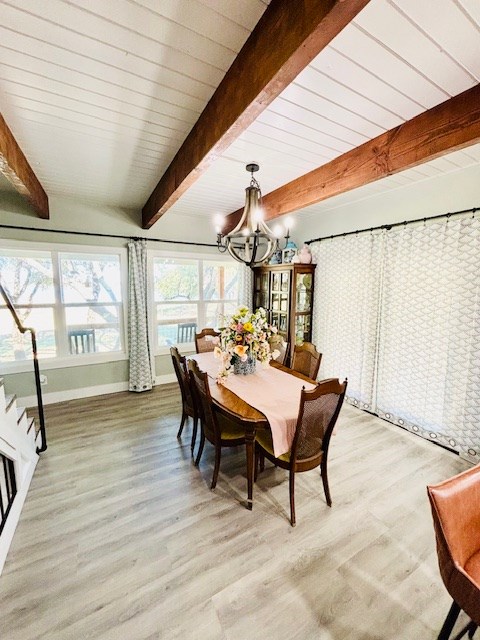 dining space featuring baseboards, an inviting chandelier, light wood-style flooring, and beam ceiling