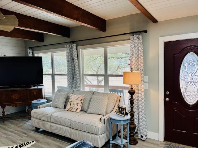 living room featuring baseboards, wood finished floors, and beamed ceiling