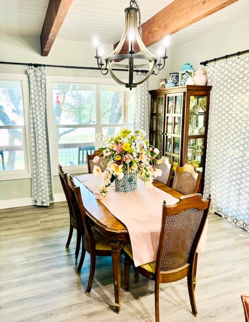 dining space featuring baseboards, a chandelier, beam ceiling, and light wood-style flooring