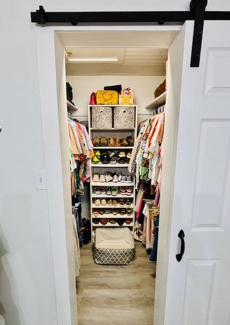 spacious closet featuring a barn door and wood finished floors