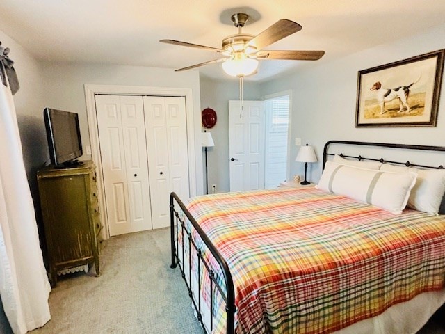 bedroom featuring a ceiling fan, a closet, and light colored carpet