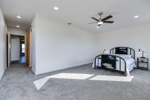 carpeted bedroom with ceiling fan and a barn door