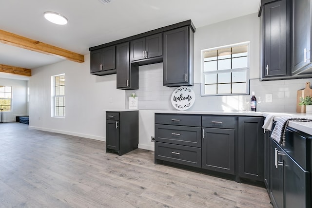 kitchen with light wood-type flooring, beam ceiling, and decorative backsplash