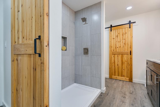 bathroom featuring wood-type flooring, tiled shower, and vanity