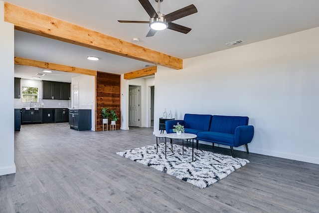 living room featuring hardwood / wood-style floors, sink, beamed ceiling, and ceiling fan