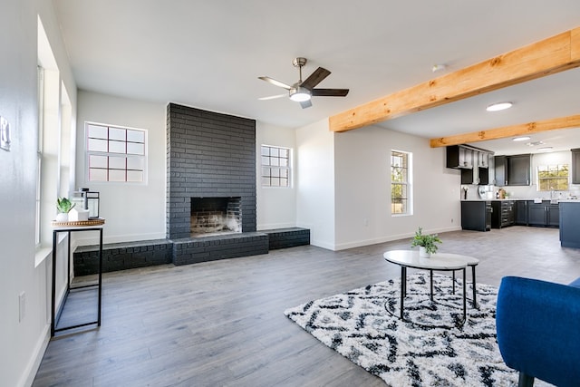 living room with ceiling fan, a fireplace, beam ceiling, and hardwood / wood-style floors