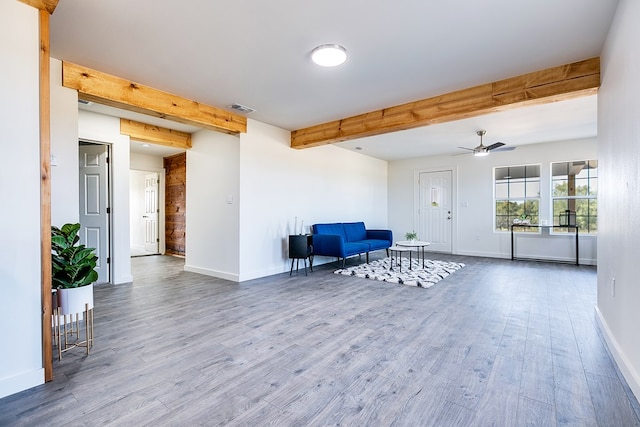 unfurnished room featuring wood-type flooring, ceiling fan, and beam ceiling