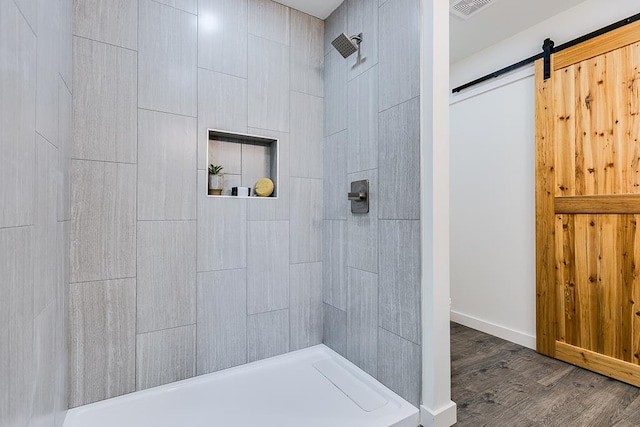 bathroom with wood-type flooring and a tile shower