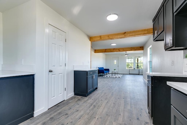 kitchen featuring ceiling fan, light wood-type flooring, and beam ceiling