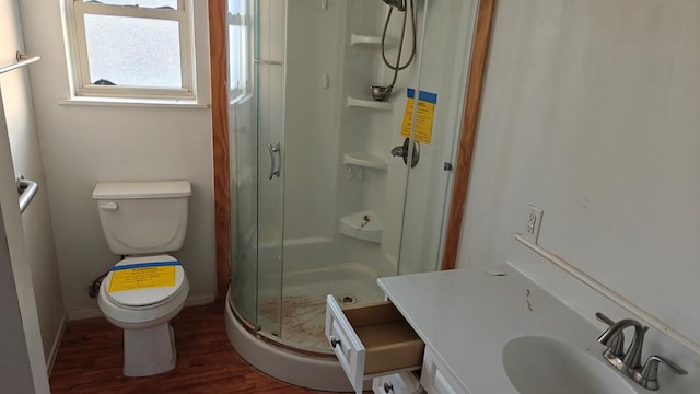 bathroom featuring hardwood / wood-style flooring, vanity, toilet, and a shower with door