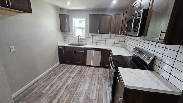 2514 S Hill St, San Angelo, TX 76903 - kitchen with decorative backsplash, stainless steel appliances, light wood finished floors, a sink, and baseboards