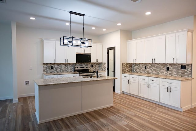 kitchen with an island with sink, white cabinetry, light wood-style floors, and appliances with stainless steel finishes