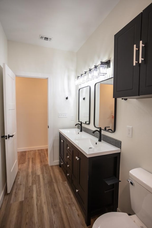 bathroom featuring a sink, visible vents, toilet, and wood finished floors