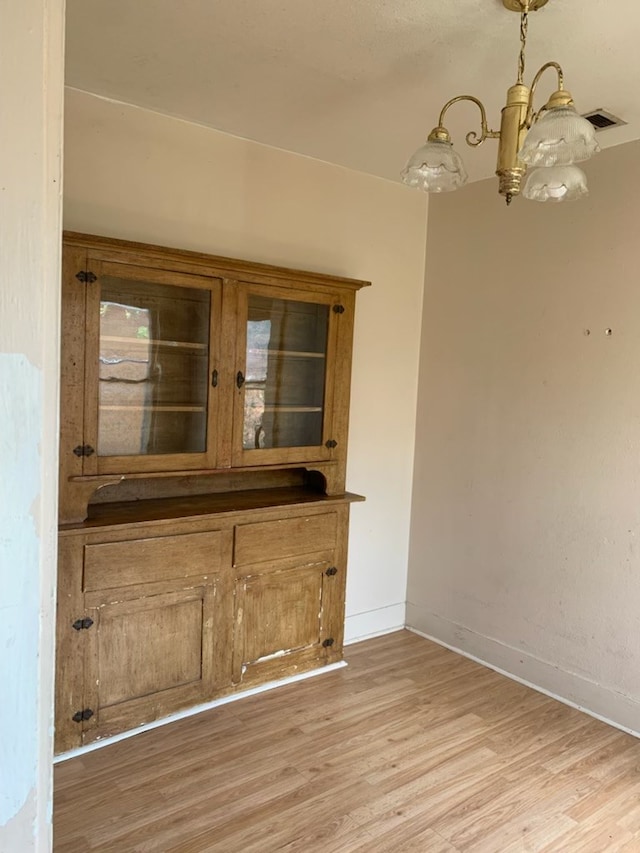 606 Pulliam St, San Angelo, TX 76903 - unfurnished dining area featuring a chandelier, light wood-style flooring, and baseboards