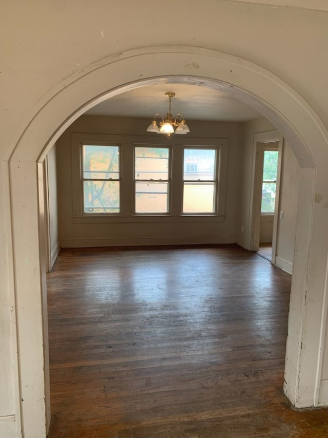 606 Pulliam St, San Angelo, TX 76903 - unfurnished room featuring arched walkways, a chandelier, dark wood-style flooring, and baseboards
