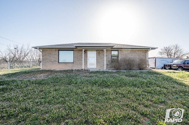 view of front of house with brick siding, a front yard, and fence