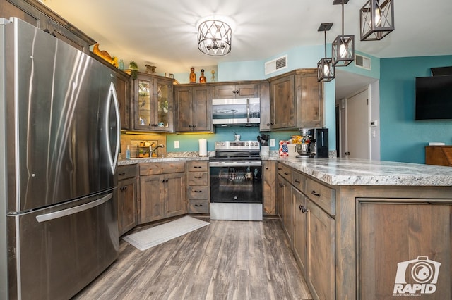 kitchen with visible vents, appliances with stainless steel finishes, dark wood-type flooring, and a peninsula