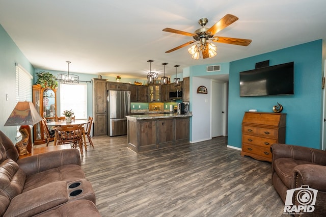 living room with visible vents, baseboards, dark wood finished floors, and ceiling fan with notable chandelier