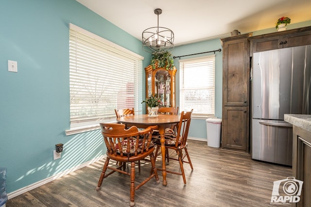 dining space featuring dark wood-style floors, an inviting chandelier, and baseboards