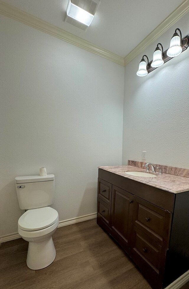 bathroom featuring vanity, hardwood / wood-style floors, crown molding, and toilet