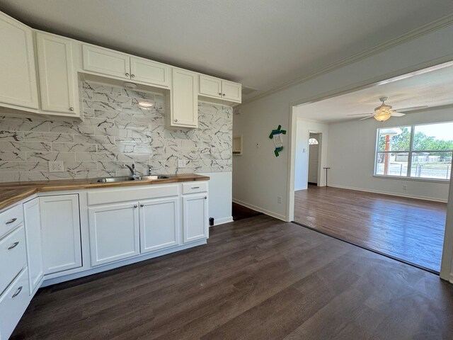 kitchen with butcher block countertops, sink, and white cabinets