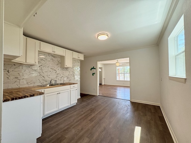 kitchen with dark hardwood / wood-style floors, white cabinetry, sink, wooden counters, and ornamental molding