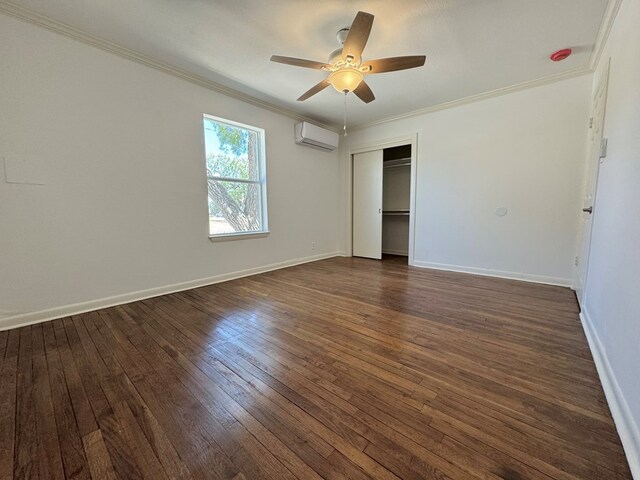 unfurnished bedroom with an AC wall unit, dark hardwood / wood-style floors, ornamental molding, ceiling fan, and a closet