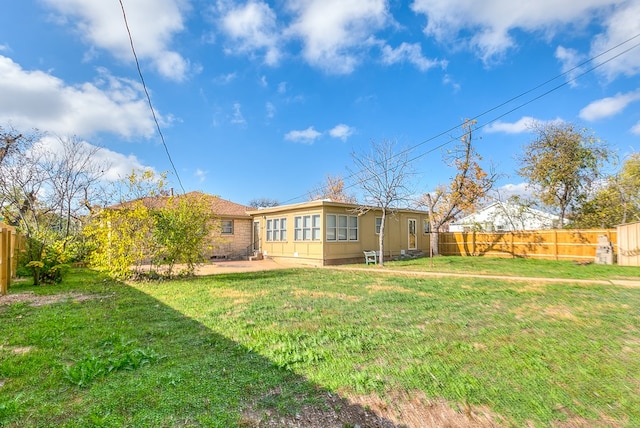 rear view of house with a patio area, a fenced backyard, and a yard