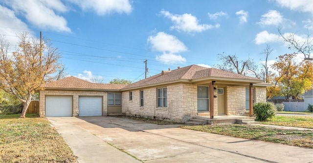 ranch-style home featuring driveway, a shingled roof, stone siding, an attached garage, and fence