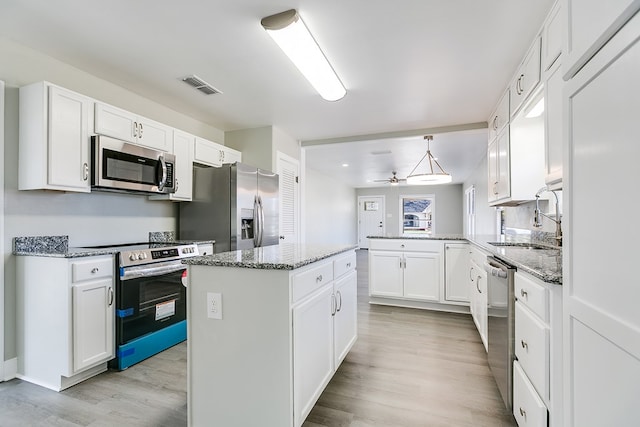 kitchen with a peninsula, a sink, visible vents, white cabinets, and appliances with stainless steel finishes