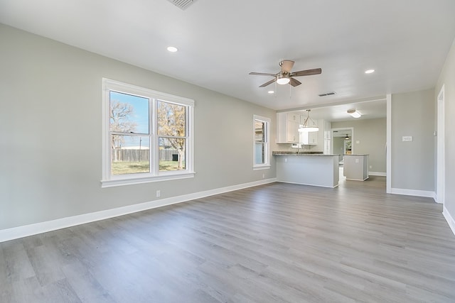 unfurnished living room with ceiling fan, recessed lighting, wood finished floors, visible vents, and baseboards