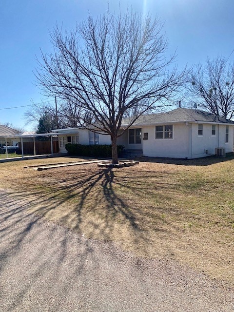 view of front of home with central AC unit and a front yard