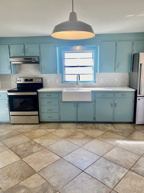 kitchen with tasteful backsplash, stainless steel appliances, decorative light fixtures, and sink