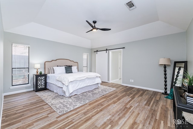 3421 Clearview Dr, San Angelo, TX 76904 - bedroom featuring wood finished floors, a tray ceiling, vaulted ceiling, a barn door, and a ceiling fan