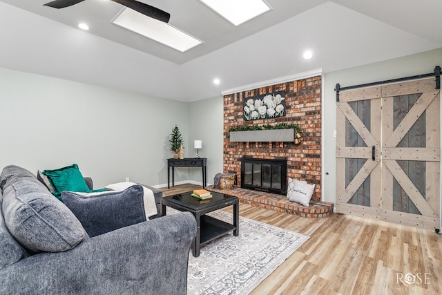 3421 Clearview Dr, San Angelo, TX 76904 - living room featuring lofted ceiling, wood finished floors, a barn door, a brick fireplace, and a ceiling fan