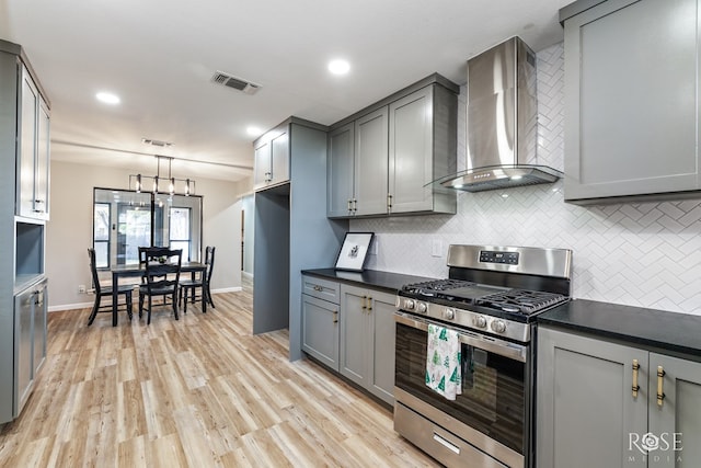 3421 Clearview Dr, San Angelo, TX 76904 - kitchen featuring wall chimney exhaust hood, stainless steel range with gas stovetop, gray cabinets, decorative backsplash, and dark countertops