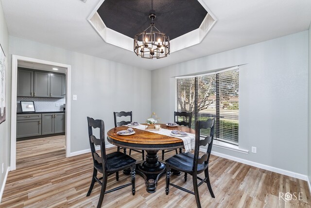 3421 Clearview Dr, San Angelo, TX 76904 - dining space with light wood-style floors, a chandelier, and a raised ceiling
