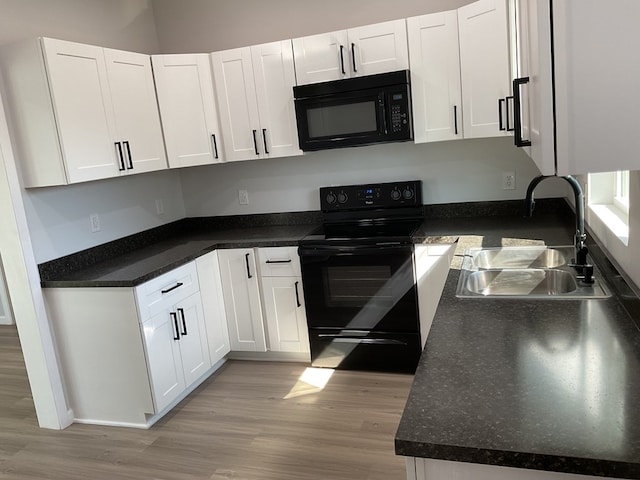 kitchen with sink, black appliances, white cabinets, and light wood-type flooring