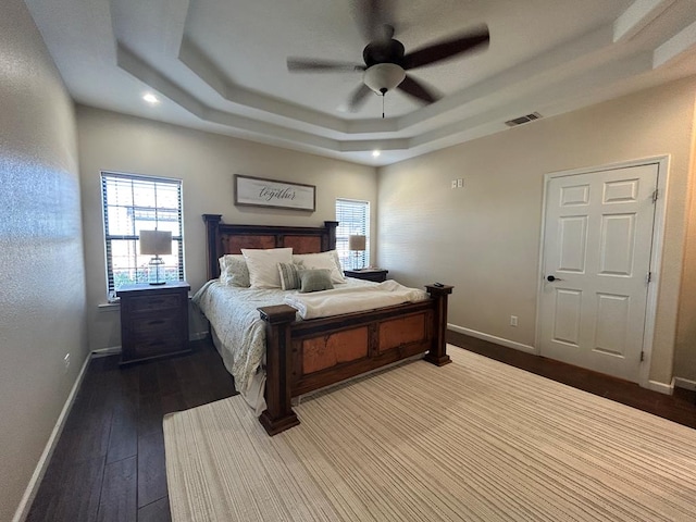 bedroom with wood-type flooring, a raised ceiling, and ceiling fan