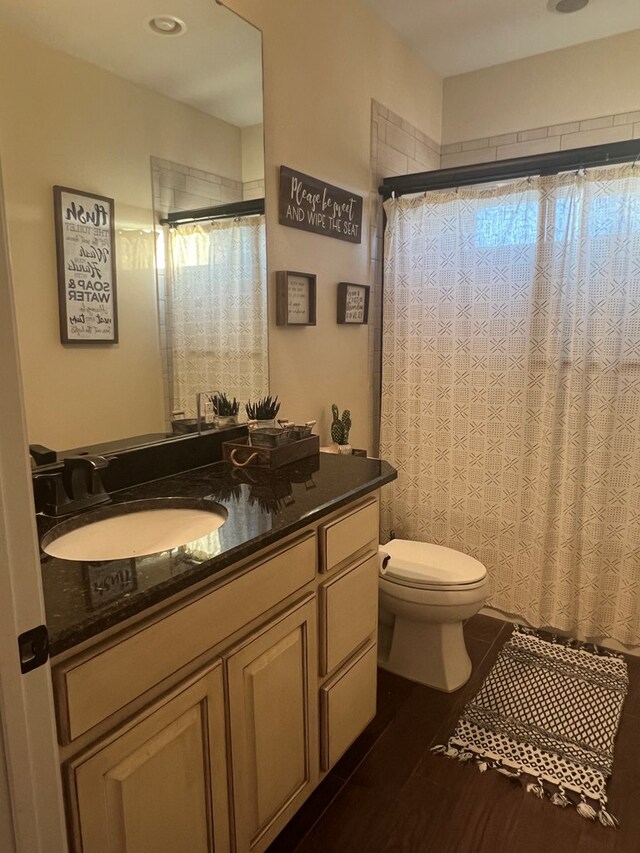 bathroom featuring hardwood / wood-style flooring, vanity, a shower with shower curtain, and toilet