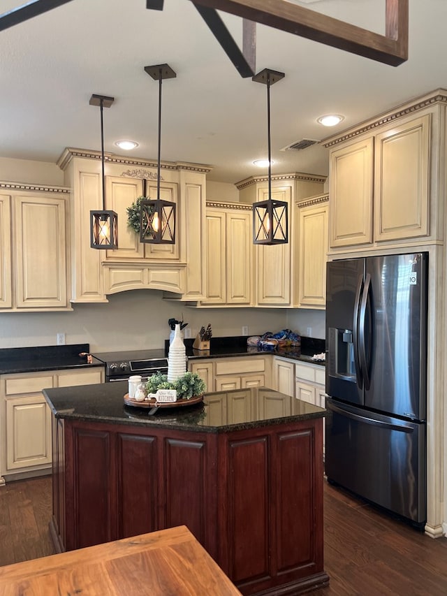 kitchen featuring stainless steel appliances, cream cabinetry, and decorative light fixtures