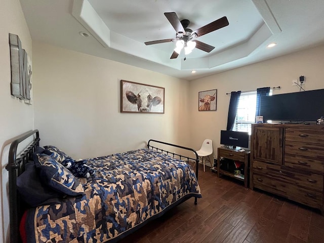 bedroom featuring a raised ceiling, dark hardwood / wood-style floors, and ceiling fan