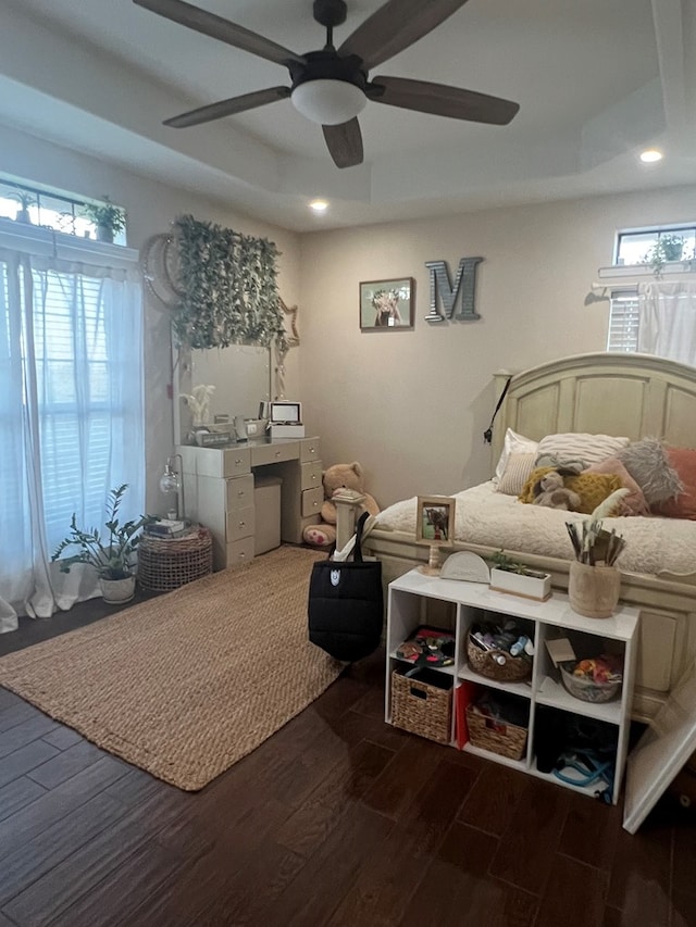 bedroom with ceiling fan, a tray ceiling, and dark hardwood / wood-style flooring