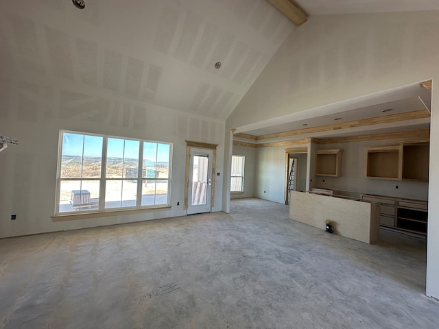 unfurnished living room featuring beamed ceiling and a high ceiling