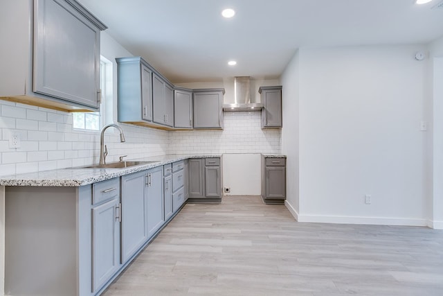 2624 Dallas St, San Angelo, TX 76903 - kitchen featuring a sink, gray cabinetry, wall chimney range hood, light wood-style floors, and tasteful backsplash