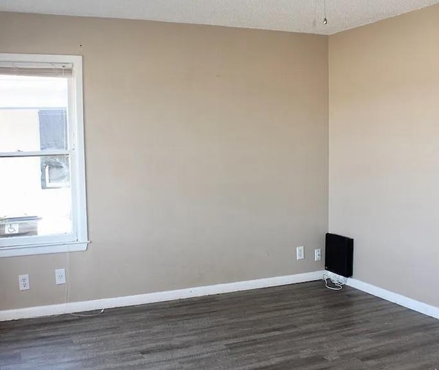 unfurnished room with dark wood-style floors, baseboards, and a textured ceiling