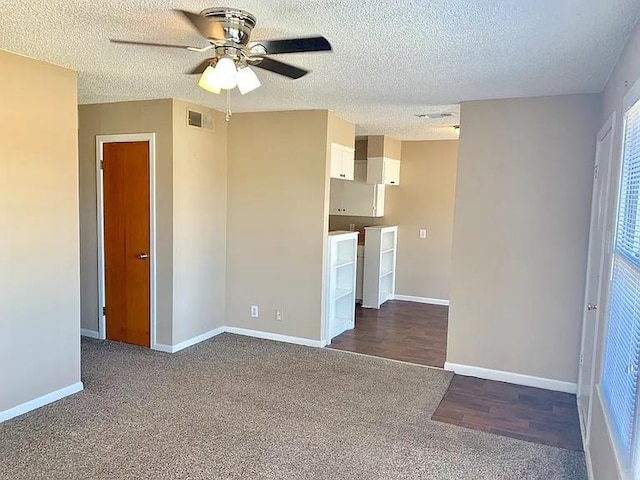 unfurnished living room featuring visible vents, carpet flooring, a textured ceiling, and baseboards