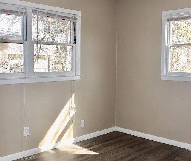 empty room featuring dark wood-style floors, baseboards, and a wealth of natural light