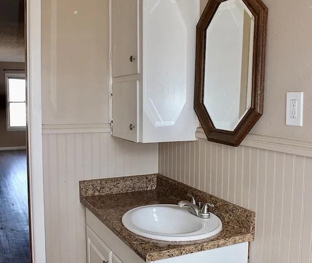 bathroom with vanity, wood finished floors, and wainscoting